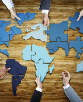 group of business people with jigsaw puzzle forming in world map
